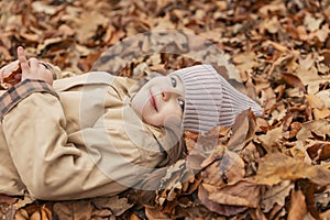 portrait of a little girl lying in fallen leaves