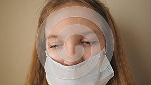 Portrait of little girl with medical face mask during self isolation. Sad female child wear protective mask from virus