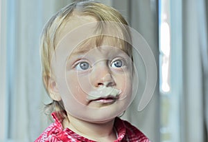 Portrait of a little girl with milk moustaches.