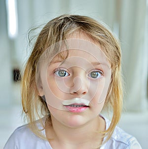 Portrait of a little girl with milk moustaches.