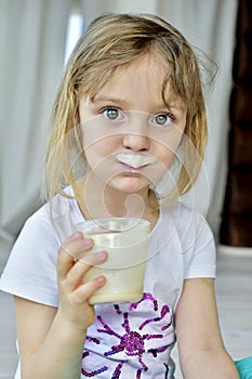 Portrait of a little girl with milk moustaches.