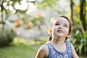 Portrait little girl in nature park . cute kid looking up.