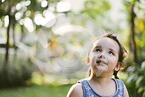 Portrait little girl in nature park . cute kids looking up.