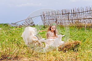 Portrait of little girl outdoors in summer.Girl and goat