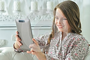 Portrait of little girl in pajama using digital tablet at home