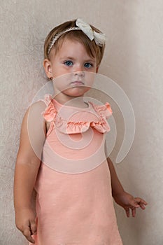 Portrait of a little girl in a pink dress and a white hair band in her hair