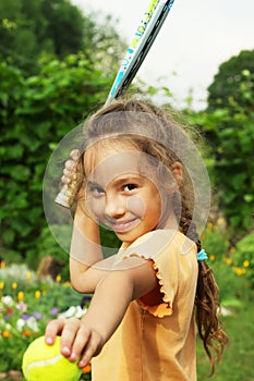 Portrait of little girl playing tennis outdoors