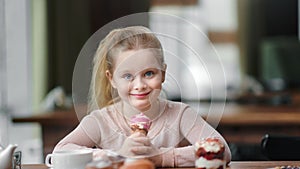 Portrait of little girl posing with ice cream cornet at cafe. Medium close up shot on 4k RED camera