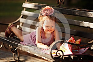 Portrait of a little girl reading a children's book lying on a p