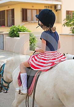 Portrait of little girl riding pony.