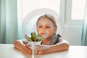 Portrait of a little girl in a room with a suculent flower