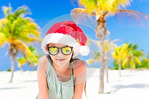 Portrait of little girl in Santa hat during Christmas beach vacation