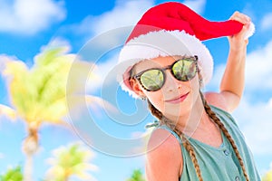 Portrait of little girl in Santa hat during Christmas beach vacation