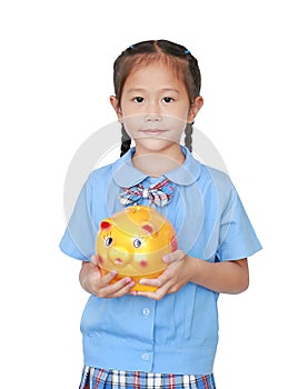 Portrait of little girl in school uniform holding piggy bank isolated on white background. Schoolgirl with money saving concept