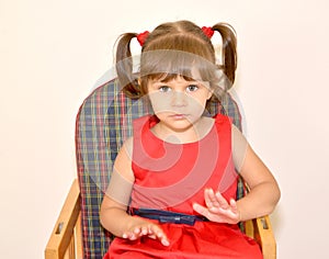 Portrait of the little girl sitting on a children's chair