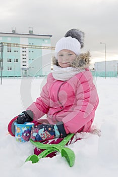 Portrait of little girl sitting on snowy ground