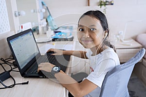 Girl smiling at camera with laptop and earphone photo
