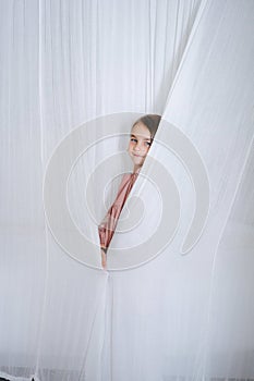 Portrait of a little girl standing behind curtains