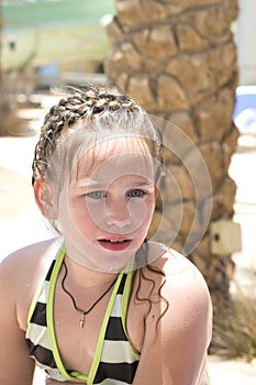 portrait of little girl in a striped swimsuit with wet hair who swam in the pool
