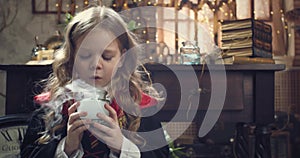 Portrait of a little girl student of the wizard school blowing steam of a jar 4k