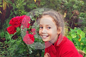 Portrait of Little Girl in the Summer time. Beautiful Girl smiling in rose Garden