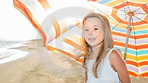 Portrait of a little girl with an umbrella on the beach