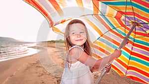 Portrait of a little girl with an umbrella on the beach