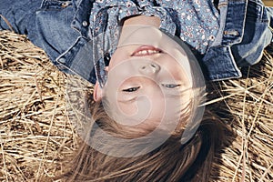 Portrait of a little girl upside down on a haystack