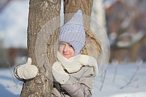 Portrait of little girl in warm wear near a tree in winter