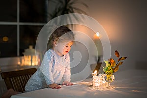 Portrait of little girl watching candles in dark room