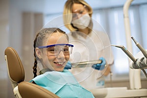 Portrait of a little girl wearing goggles sitting in a chair in the dental office