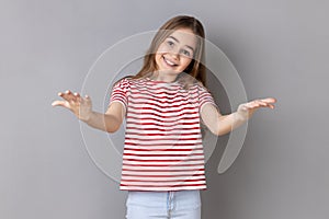 Little girl outstretching hands looking at camera with kind smile, greeting and regaling.