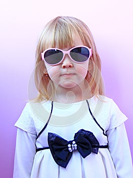 Portrait of little girl wearing sunglasses on pink background. Studio shot of young girl wearing pink sunglasses. Fashion little