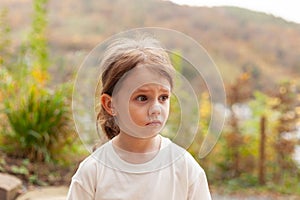 Portrait of a little girl in a white T-shirt outdoors