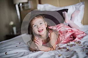 Portrait of a little girl who played on the bed in the bedroom