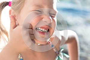 Portrait of a little girl with a wobbly baby tooth and a thumb up