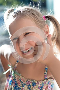 Portrait of a little girl with a wobbly baby tooth and a thumb up