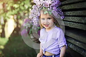 Portrait of a little girl with a wreath of lilac flowers on her head