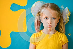 Portrait of a little girl in yellow dress on a yellow and blue background with a puzzle