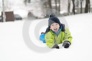 Portrait of Little Happy Boy Lies in Snow