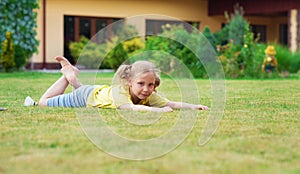 Portrait of little happy girl playing barefoot badminton at garden near her house