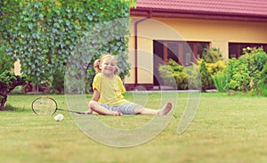 Portrait of little happy girl playing barefoot badminton at garden near her house