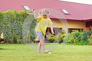 Portrait of little happy girl playing barefoot badminton at garden near her house