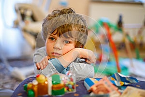 Portrait of little kid boy sad on birthday. child with lots of toy