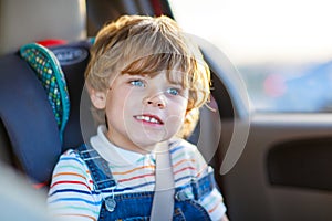 Portrait of little kid boy sitting in safety car seat