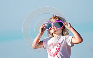 portrait of a little kid girl in big sunglasses. Child on summer sea beach
