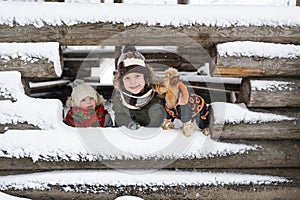 Portrait of the little kids and small dog against the background of the unfinished snow-covered house in the village