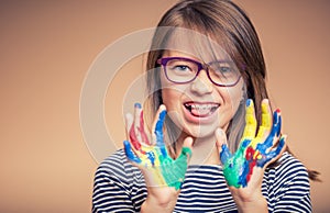 Portrait of a little pre-teen student girl showing painted hands. Toned Photo