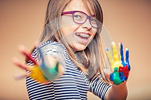 Portrait of a little pre-teen student girl showing painted hands. Toned Photo