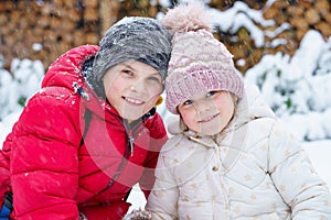 Portrait of little preschool girl and school boy playing with snow in winter. Brother and cute sister together during